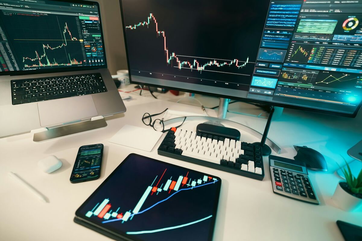 A desk with several screens showing market charts